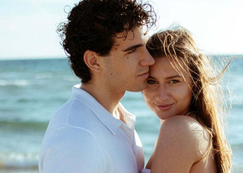 A couple embracing on a beach with the ocean in the background. 3