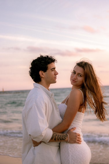 A couple embracing on a beach with the ocean in the background. 1