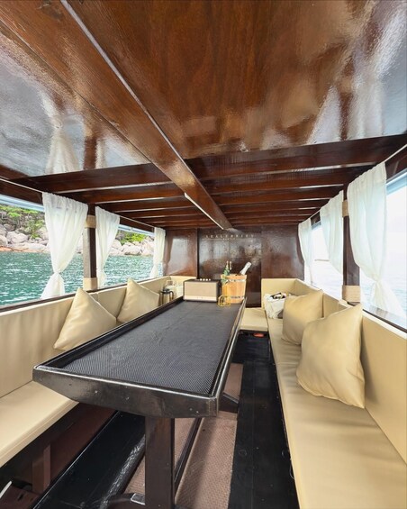 A boat interior with beige cushioned seating, a central table, and a wooden ceiling. 4