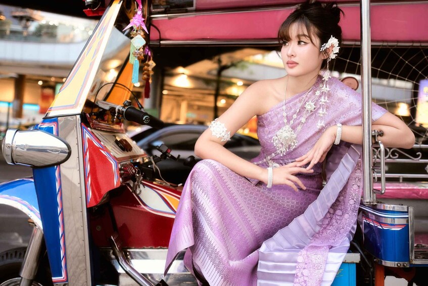 A person in a purple traditional dress sitting on a tuk-tuk. 4