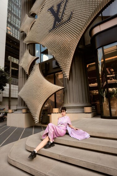 A person sitting on steps in front of a building with a large, textured sculpture. 2