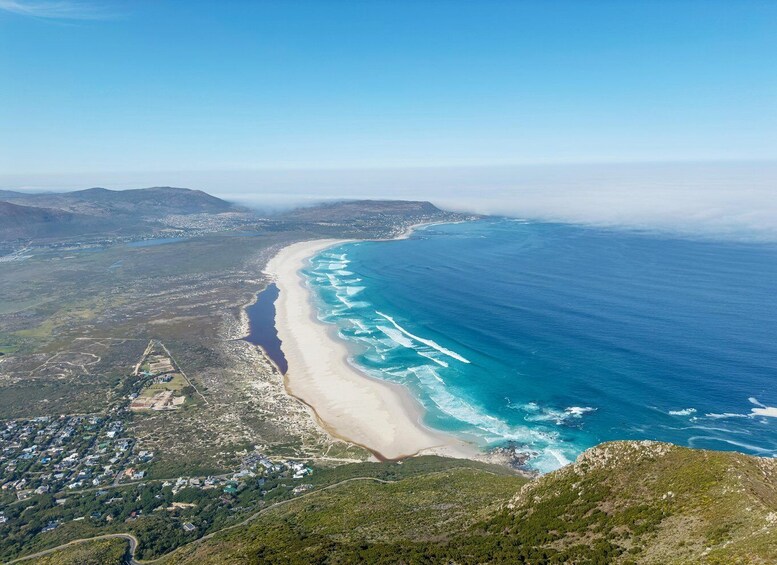 A coastal landscape with a beach, ocean, and surrounding hills. 3