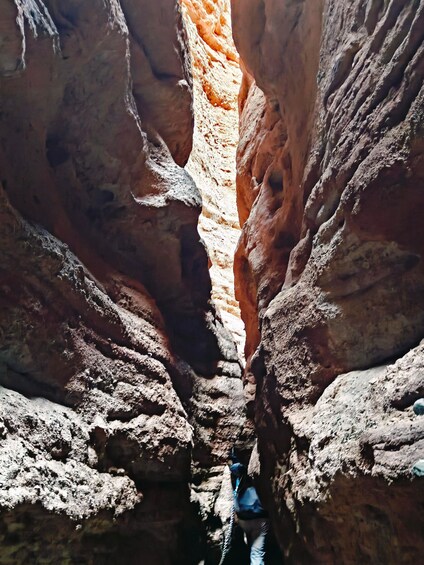 A person hiking through a narrow canyon with steep rock walls. 2