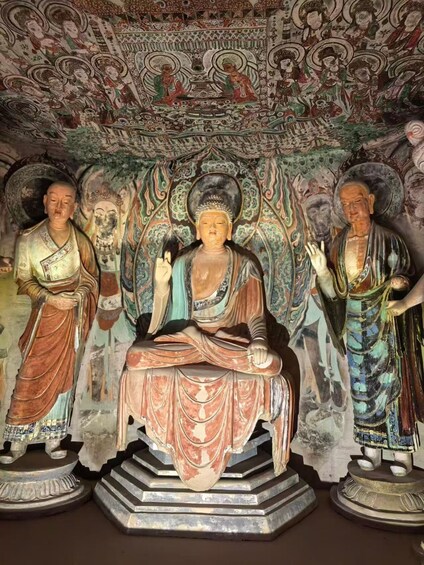 A Buddha statue with intricate murals in the background. 4