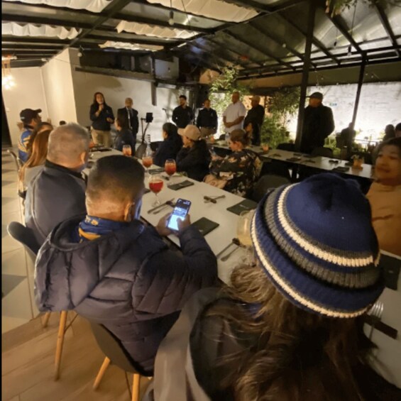 A group of people seated at tables, engaged in conversation and using smartphones. 2