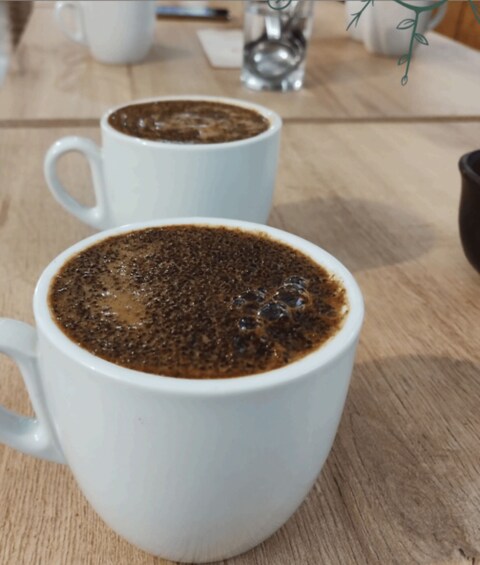 Two white ceramic cups of coffee on a wooden table. 3