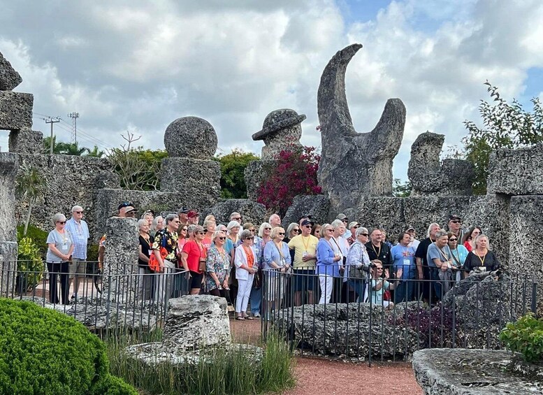 A group of people gathered around ancient stone structures in a garden setting. 1