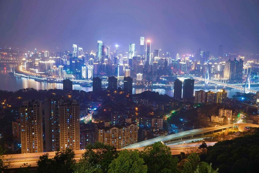 A cityscape at night with illuminated buildings, a river, and a bridge. 4