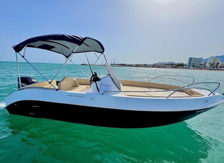 A boat with a canopy, a steering wheel, and a Suzuki logo on the back. 3