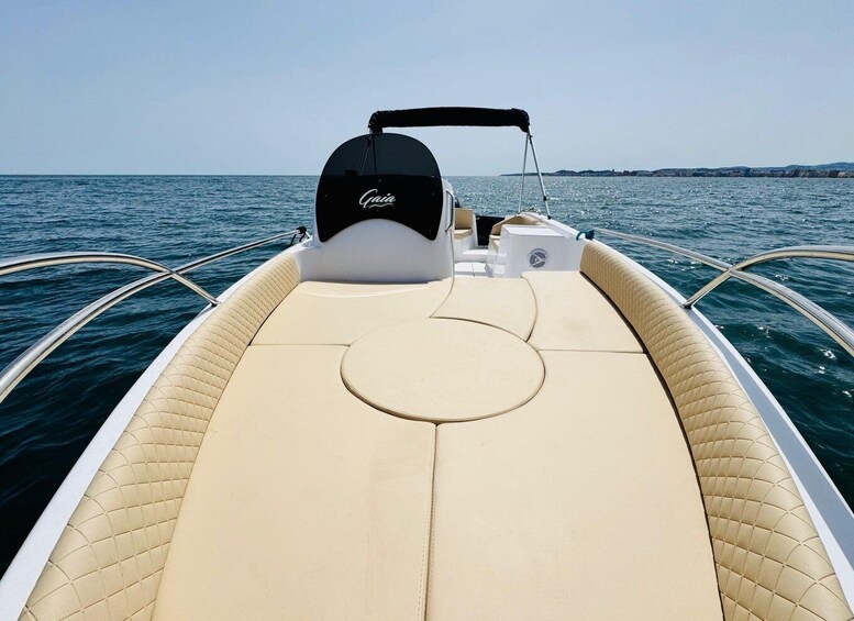 A boat with a beige deck, a black motor cover, and a logo on the side. 5