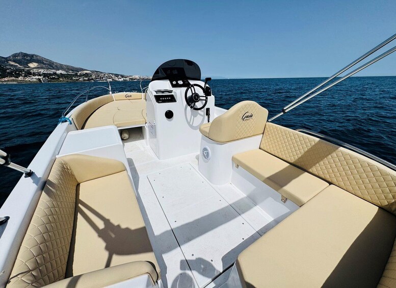 A boat's interior with beige cushioned seating and a steering wheel. 1