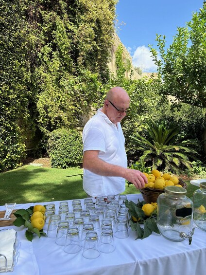 A man at an outdoor event with a table of lemons and empty glass jars. 2