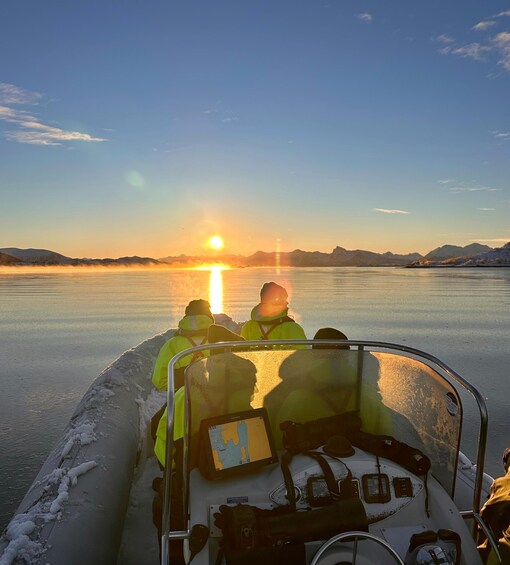 A boat with people wearing safety vests on a frozen lake at sunset. 1