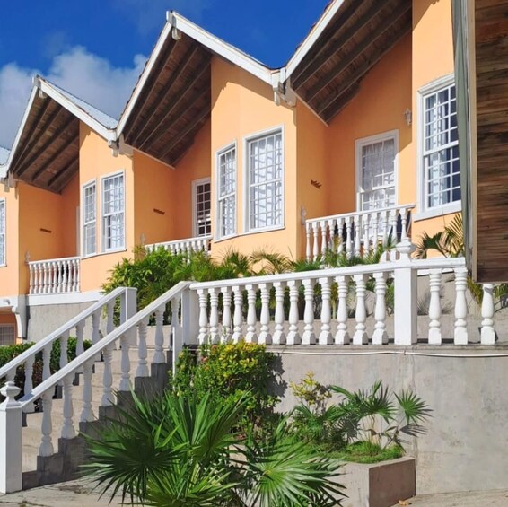 A multi-story house with a white balcony railing, orange walls, and a wooden roof. 1