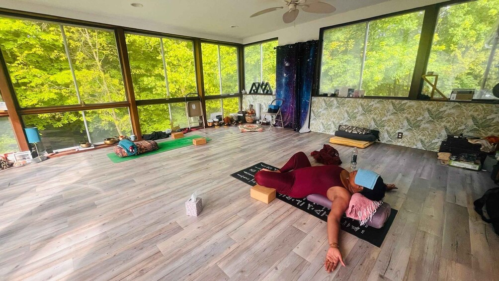 A spacious room with large windows, a yoga mat, and a person meditating. 1