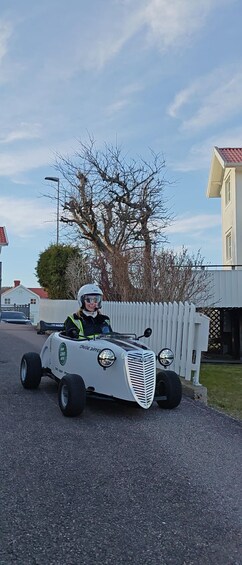 A person driving a small, white, vintage-style car with 'HOT ROD' written on the side. 4