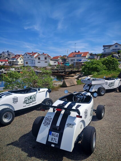 Two off-road vehicles with 'HOT ROD RIDERZ' branding parked on a gravel surface. 3