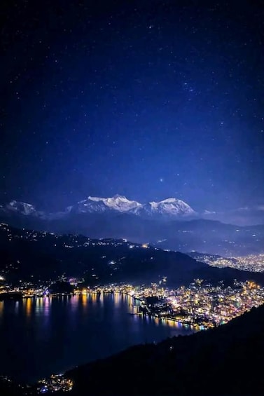 A nighttime cityscape with a mountain range in the background. 1