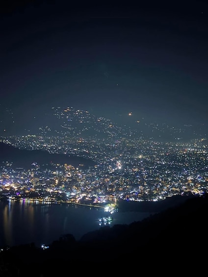 A nighttime cityscape with a dense concentration of lights along the waterfront. 3