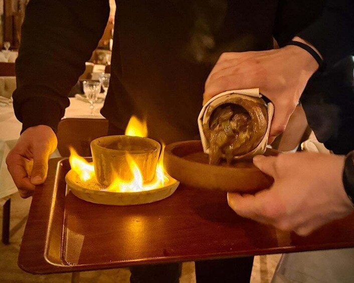 A person pouring a hot beverage onto a tray with a lit candle. 2