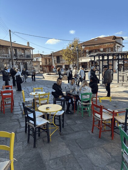 A cobblestone square with outdoor seating, people walking, and traditional buildings. 1