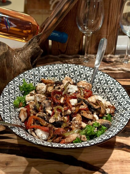 A bowl of salad with grilled chicken, red peppers, and feta cheese on a patterned plate. 5