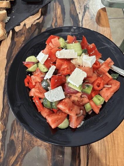 A black plate with a salad of tomatoes, cucumbers, red onions, and feta cheese. 3