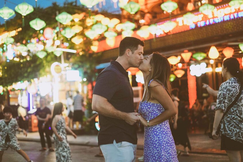 A couple embracing in a festive outdoor setting with illuminated decorations. 5