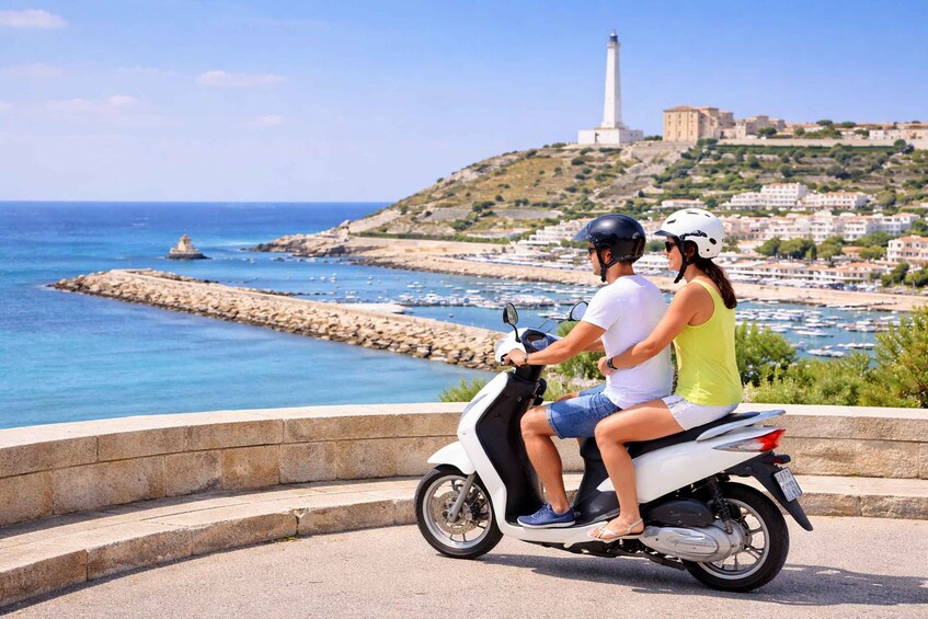 A couple on a scooter overlooking a coastal town with a lighthouse in the background. 1
