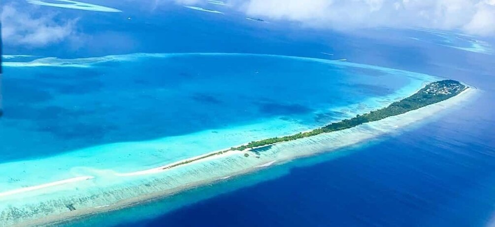 An aerial view of a turquoise coral reef surrounded by a narrow sandy beach. 1