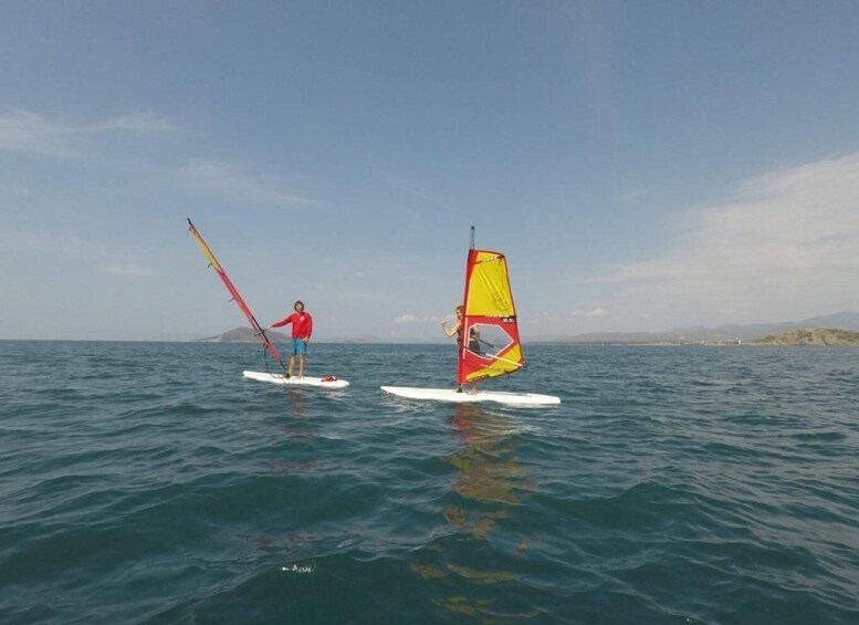 Two people windsurfing on calm sea waters with a clear sky. 5