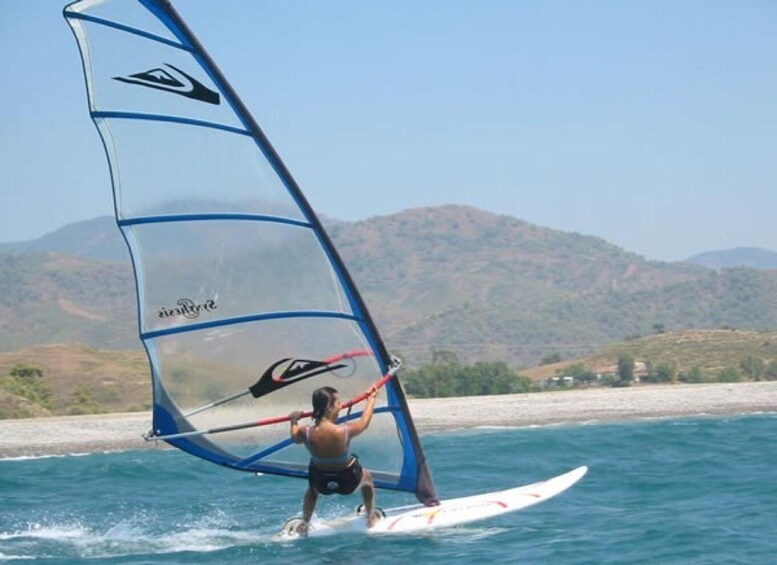 A person windsurfing on a clear day with mountains in the background. 5