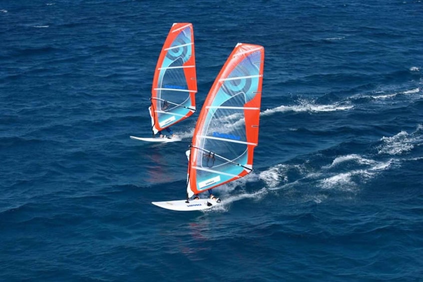 Two windsurfers on a blue ocean with white caps. 1