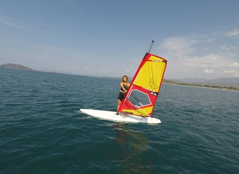 A person windsurfing on a calm sea with a clear sky. 3