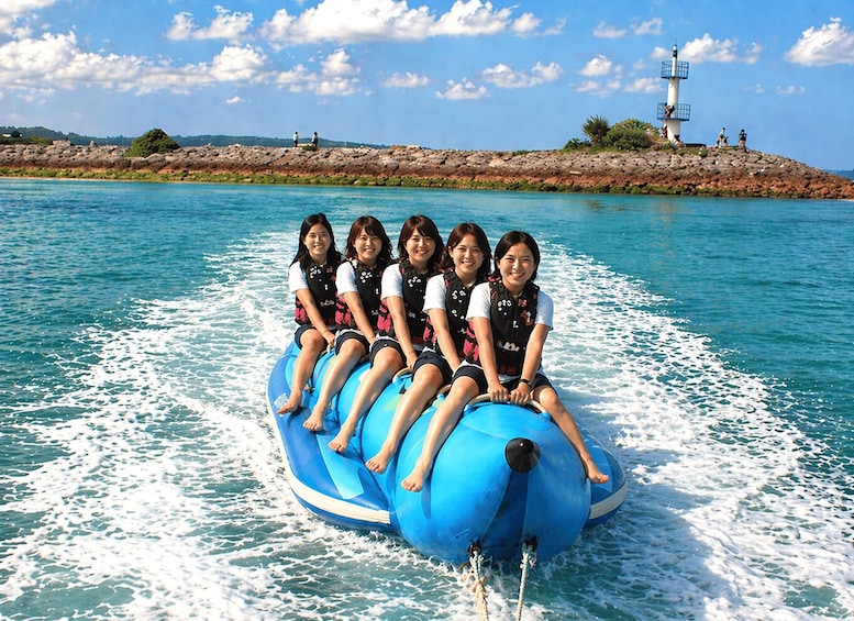 A group of people on a blue water tube ride, with a lighthouse and rocky shoreline in the background. 3