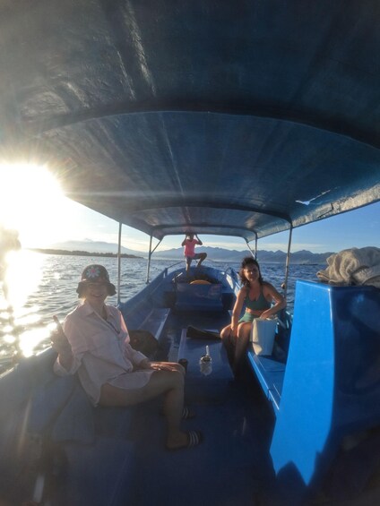 People on a boat with a canopy, a person standing, and a sunset in the background. 5