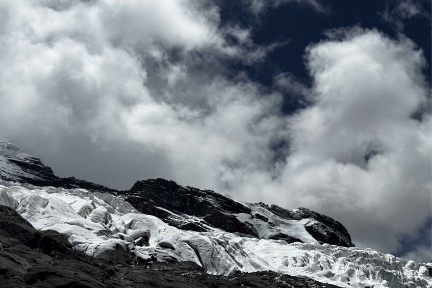 A glacier with rugged mountains in the background and a cloudy sky. 4