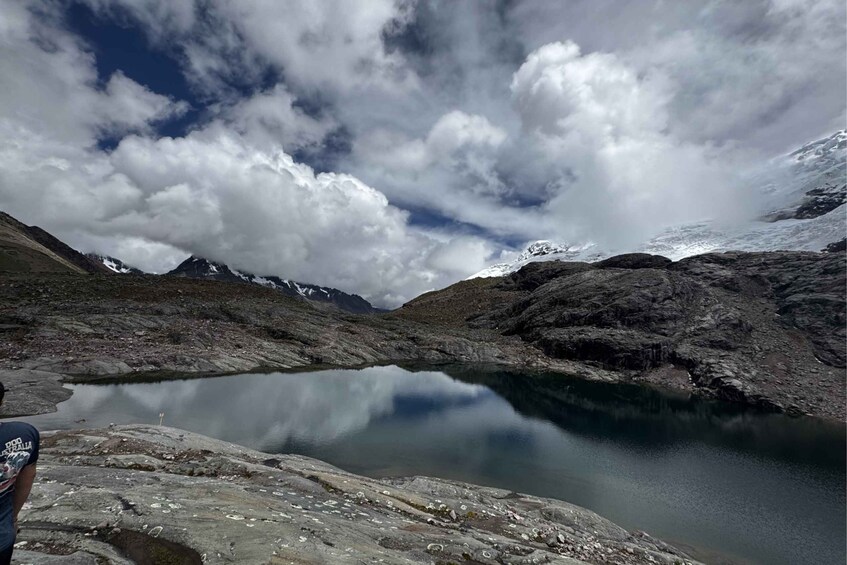 A mountain landscape with a lake reflecting the sky and surrounding peaks. 1