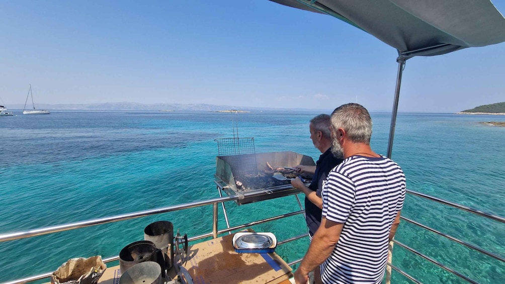 A man grilling on a boat with clear turquoise water and distant boats. 3