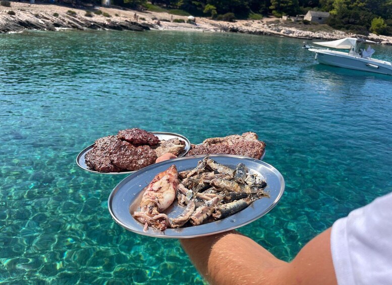 A person holding a plate with grilled meat and fish by a clear blue sea. 4