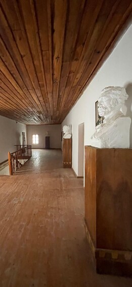 A wooden interior with a high ceiling, a staircase, and a bust sculpture. 3