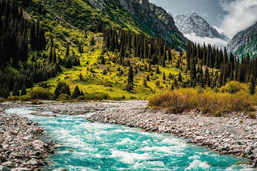 A turquoise river flowing through a mountainous landscape with dense forests and rocky terrain. 3