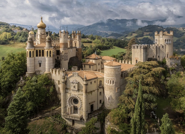 A historic castle with multiple towers and domes, surrounded by lush greenery and rolling hills. 1