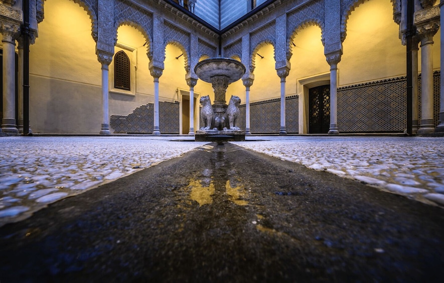 A courtyard with a fountain, arches, and patterned walls. 5
