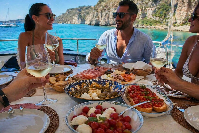 A group of people enjoying a meal on a boat with a scenic coastal backdrop. 4