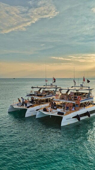 A group of boats docked at a marina with people on board. 1