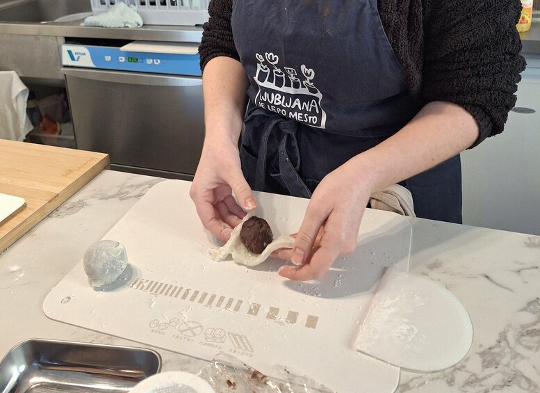 A person wearing a dark apron with a logo, preparing food on a marble countertop. 5