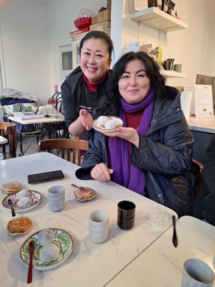 Two people at a table with food, a phone, and a cup. 2