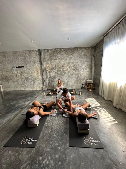 A yoga class in a room with a concrete wall and a 'breathe' sign. 5