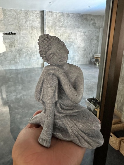 A person holding a stone Buddha statue. 3